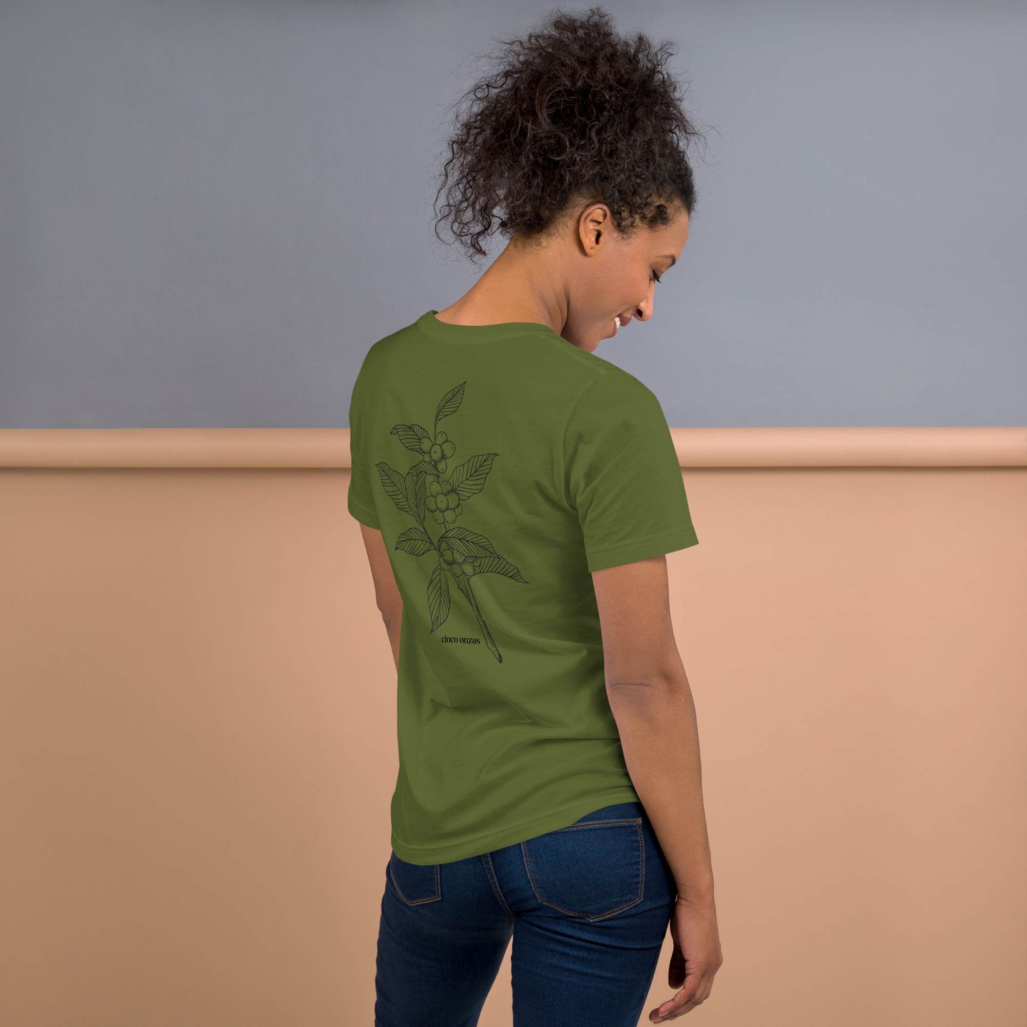 Woman wearing a green t-shirt with a coffee design on the back, standing against a plain background.